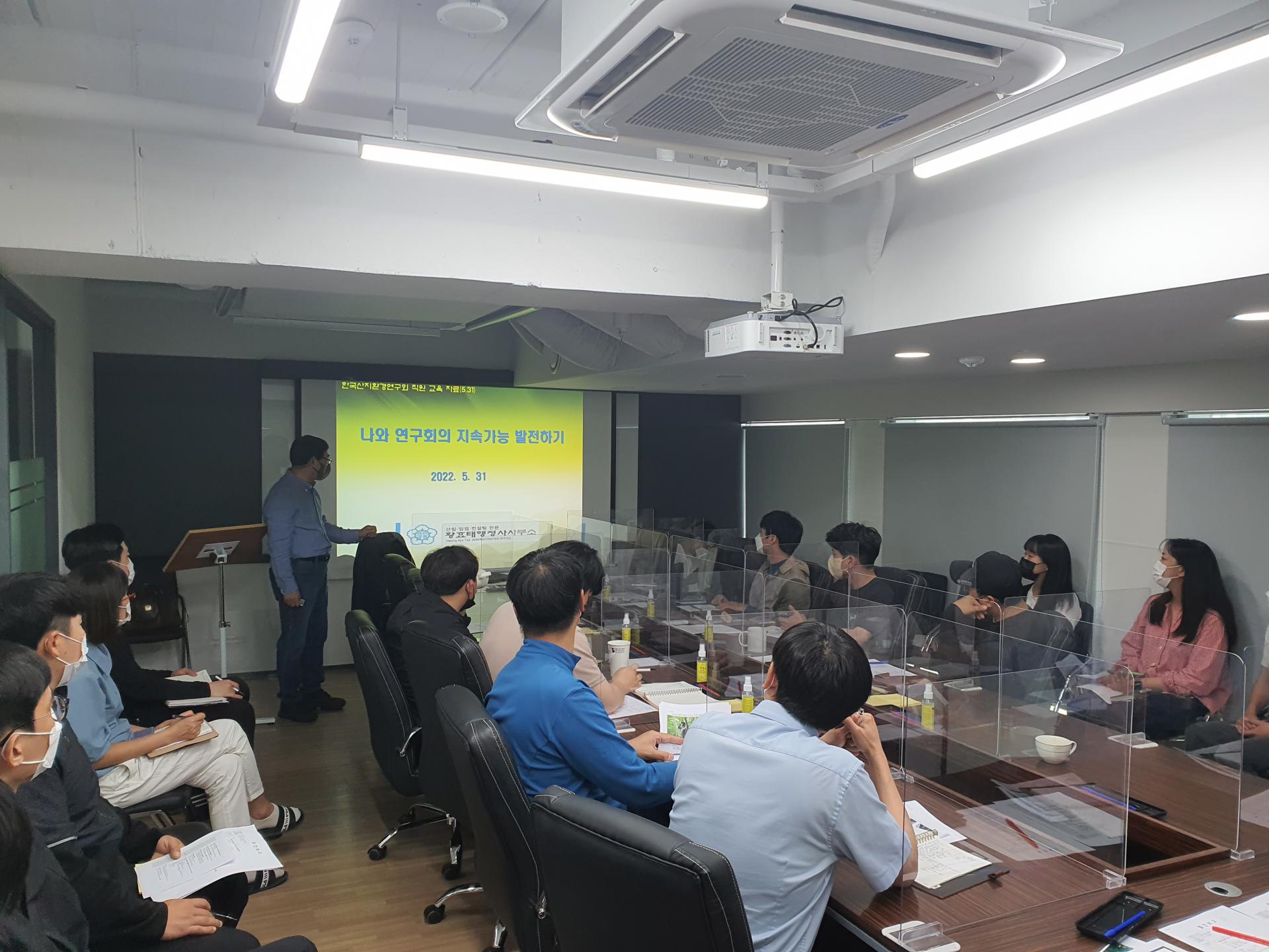 전문가 초빙교육: 강사가 발표 화면을 띄우고 회의실에서 직원들에게 강의하는 모습