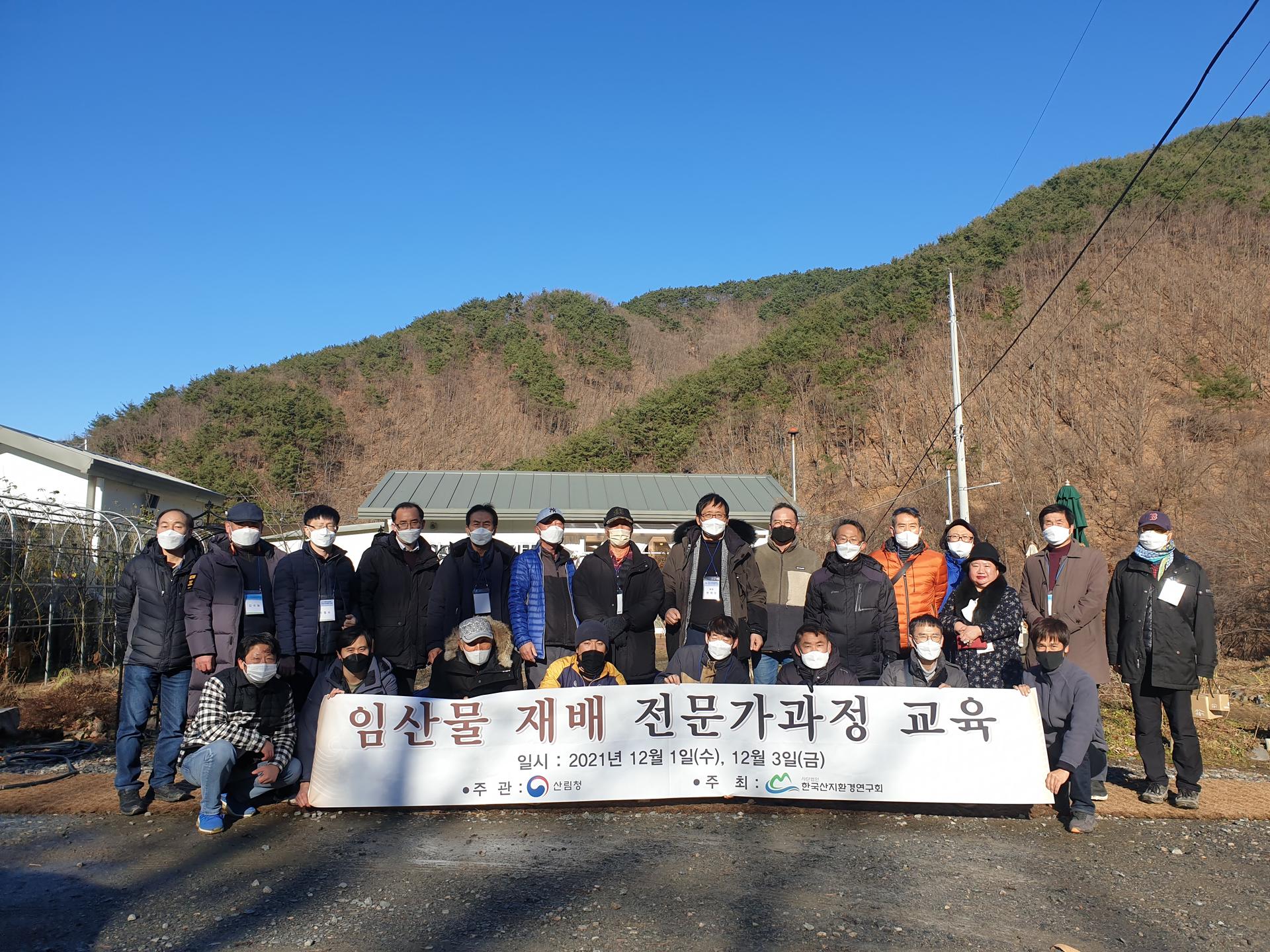 산기슭 교육장 앞에서 수강생들이 현수막을 들고 단체로 기념하는 모습